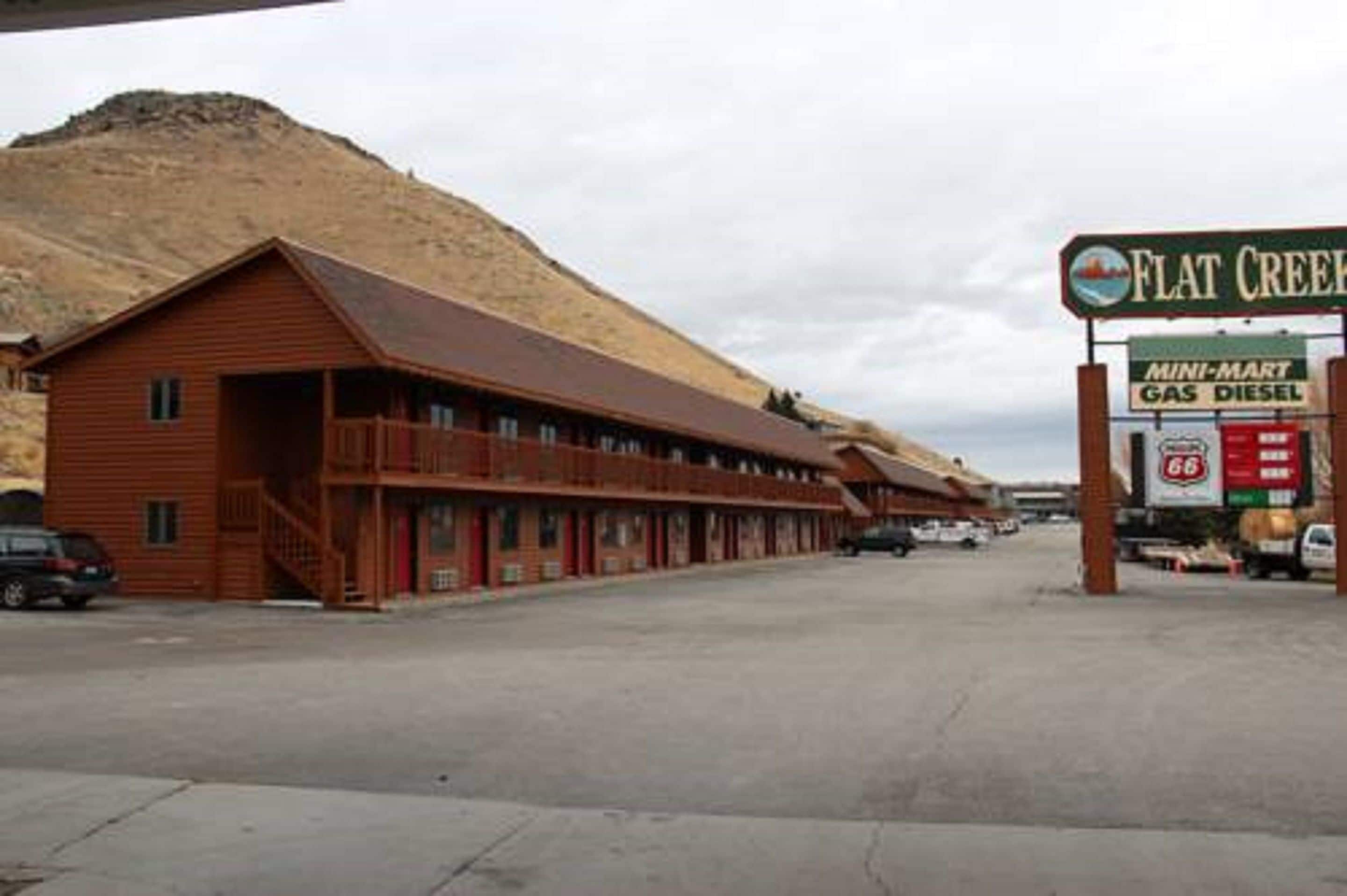 A motel with a long, single-story structure, a flat roof, and a small front porch.