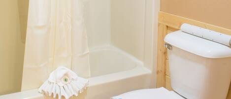 A bathroom with a shower curtain, a toilet, and a bathtub.