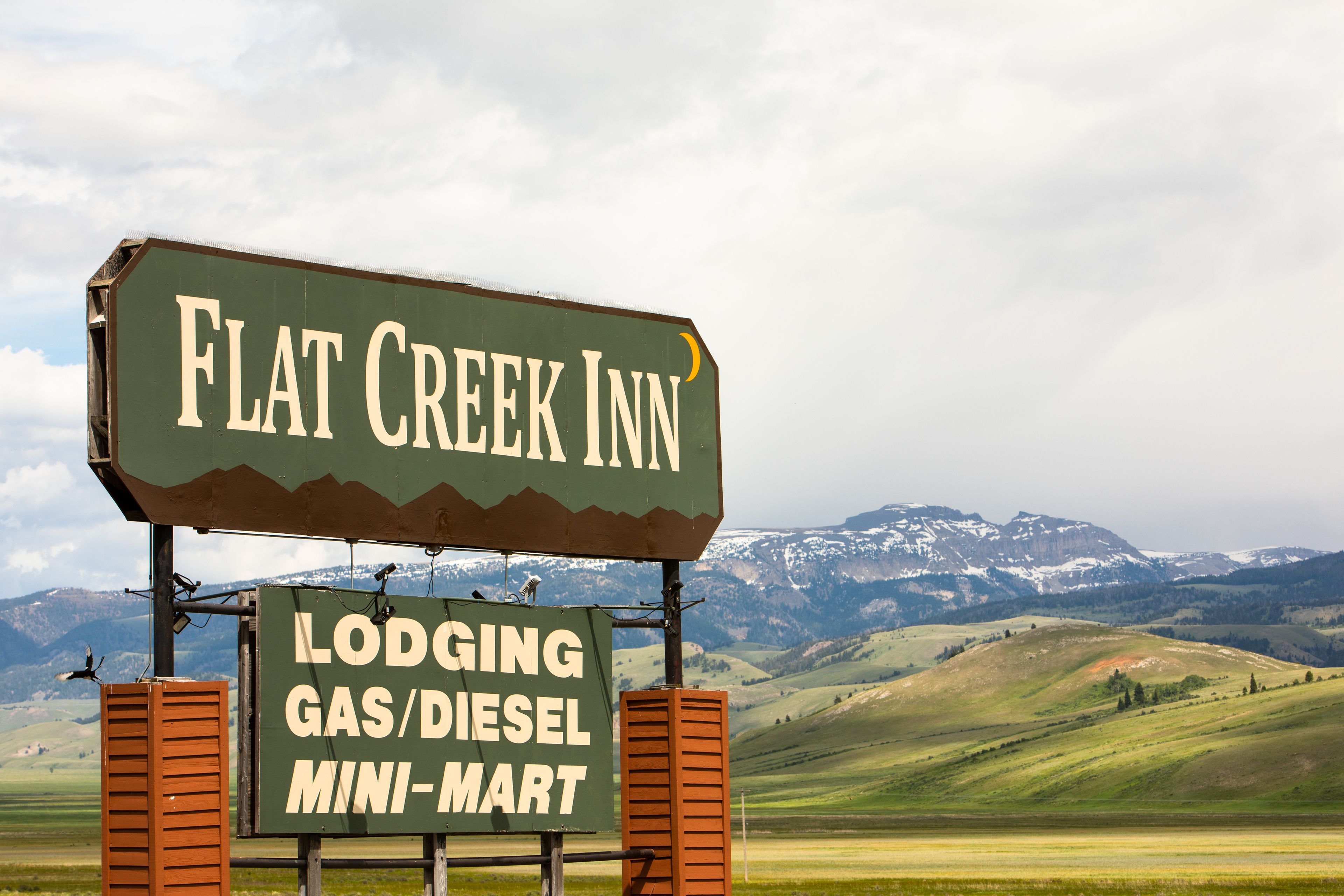 Une enseigne indiquant l’emplacement du Flat Creek Inn, avec une vue sur les montagnes en arrière-plan.