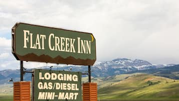 Señal de Flat Creek Inn con vista a montañas al fondo.
