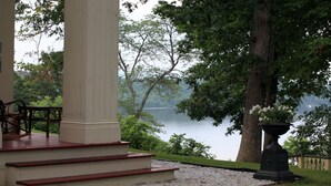 A covered porch with steps leading to a seating area overlooking a lake.