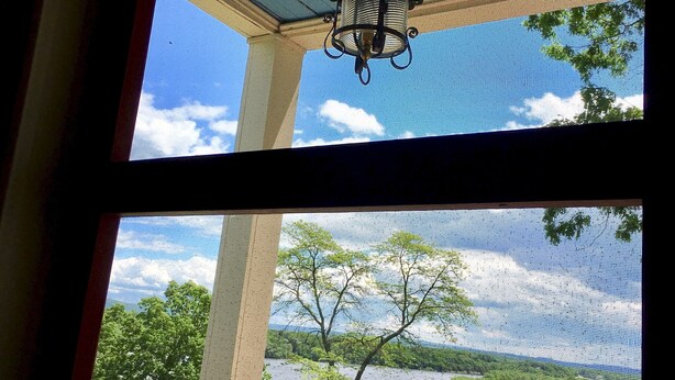 A room with a view of a lake and trees through a window.