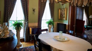 A dining room with a round table, chairs, a chandelier, and a radiator.