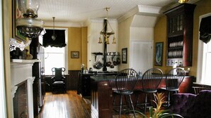 A kitchen with wooden floors, a dining area with chairs, a fireplace, and a chandelier.
