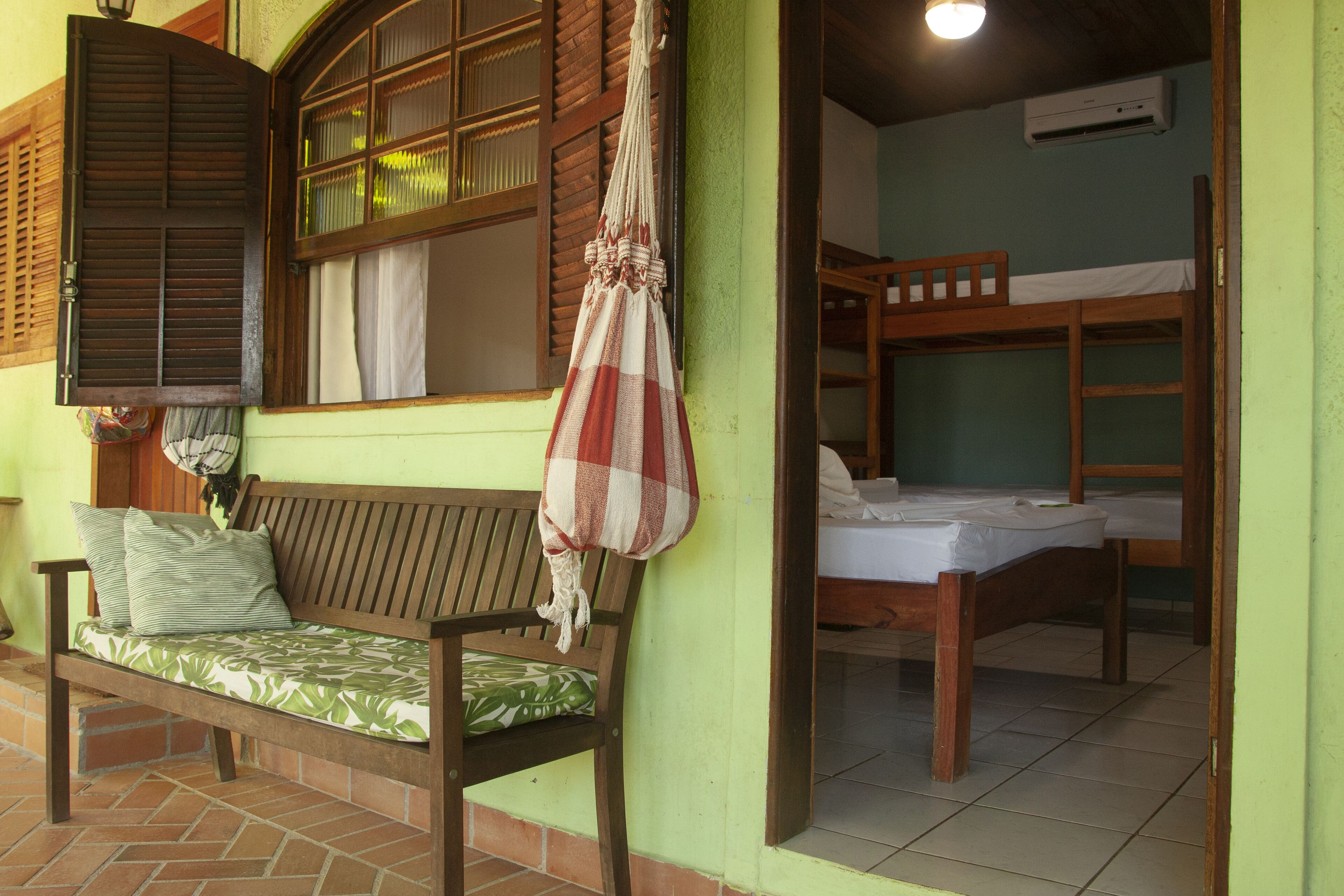 A room with a wooden bench, a bunk bed, and a hanging hammock.