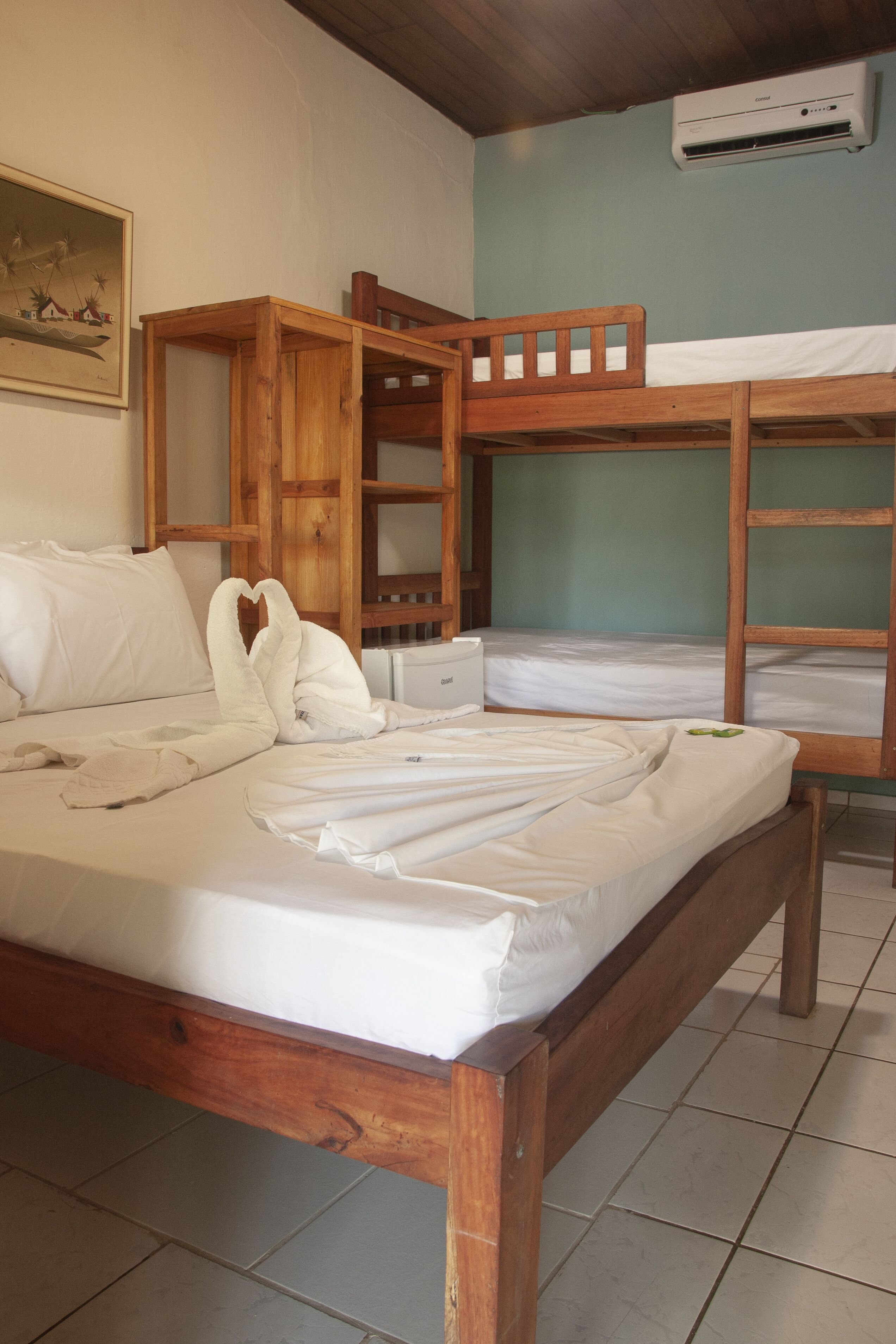 A room with a wooden bed, a wooden bench, and a small table.