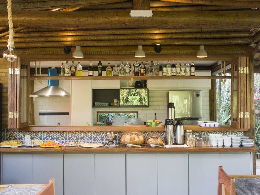 Une cuisine avec un plafond en bois, un coin bar avec différentes bouteilles, et une vue sur la salle à manger.