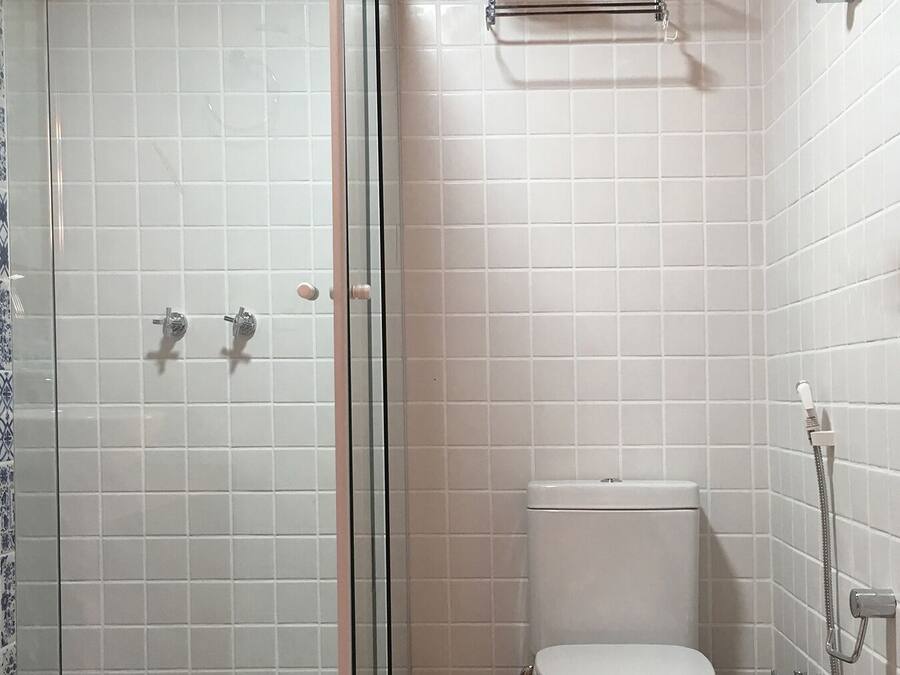 A bathroom with a glass-enclosed shower, a toilet, and a towel rack.