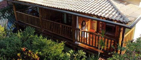 A traditional wooden house with a tiled roof, surrounded by lush greenery.