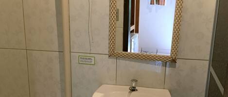 Ein Badezimmer mit Toilette, einem Waschbecken auf Säule und einem Spiegel mit Zierrahmen.