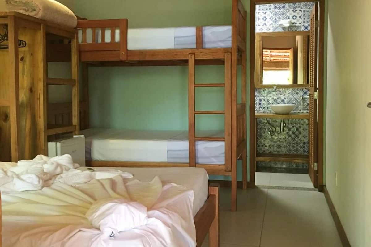 A room with bunk beds, a wooden wardrobe, a ceiling fan, and a tiled floor.