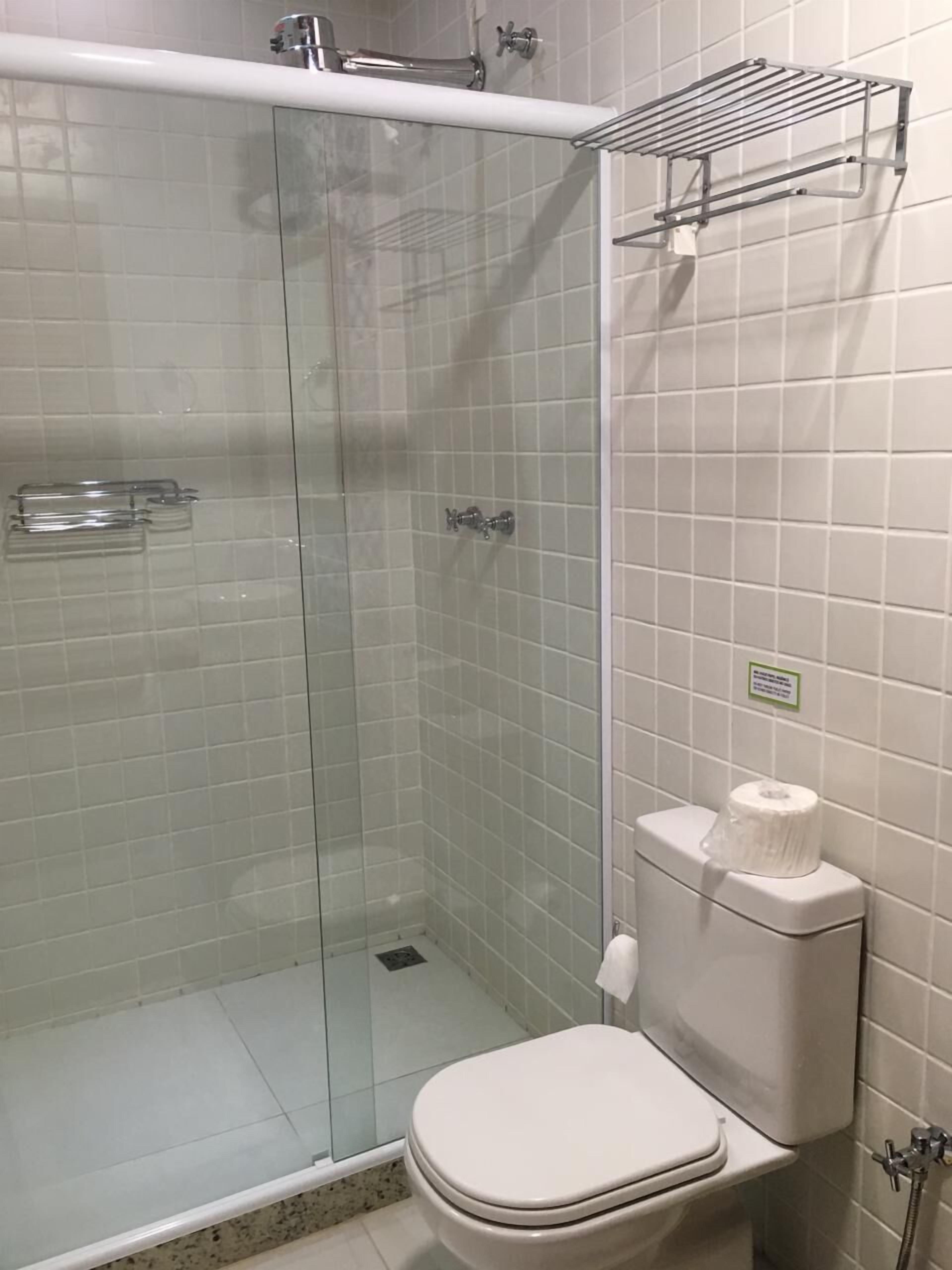 A bathroom with a glass-enclosed shower, a toilet, and a towel rack.