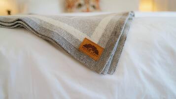 A neatly made bed with a gray and white striped blanket and a brown tag.