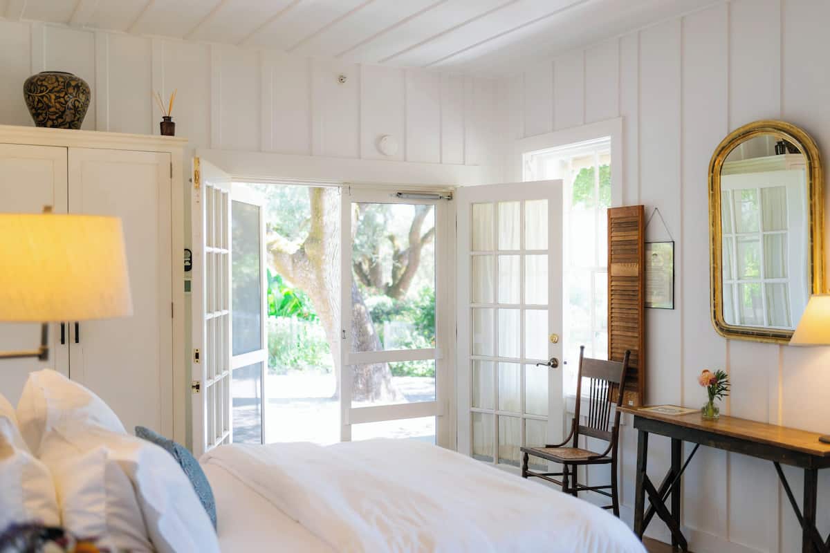 A bedroom with a bed, a desk, a chair, and a large mirror.