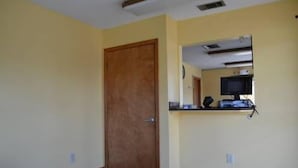 A room with a wooden door, a small stone bench, and a kitchenette area with a microwave and a small counter. - Royal Inn of New Orleans (New Orleans)