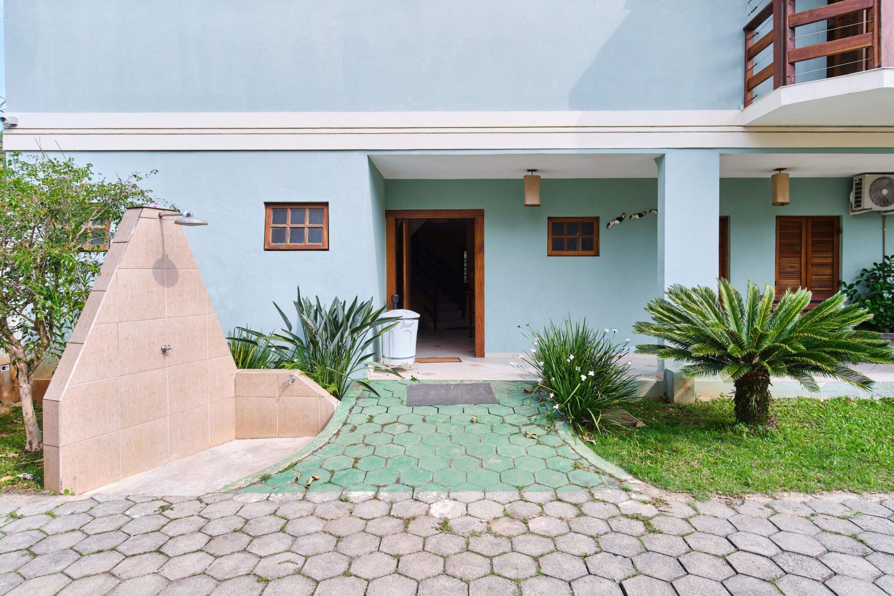 A two-story building with a light blue exterior, a covered entrance, and a paved pathway leading to the door.