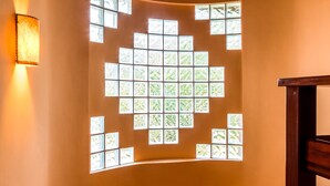 Una escalera con barandilla de madera y una pared con diseño geométrico en la ventana.