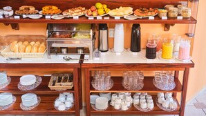 Un bufé con diversas opciones de comida y bebidas, como frutas, sándwiches y cereales.