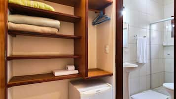 A bathroom with a wooden shelf unit holding towels, a white sink, and a toilet.
