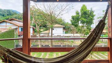 A hammock hanging in a wooden structure with a view of houses and trees in the background.
