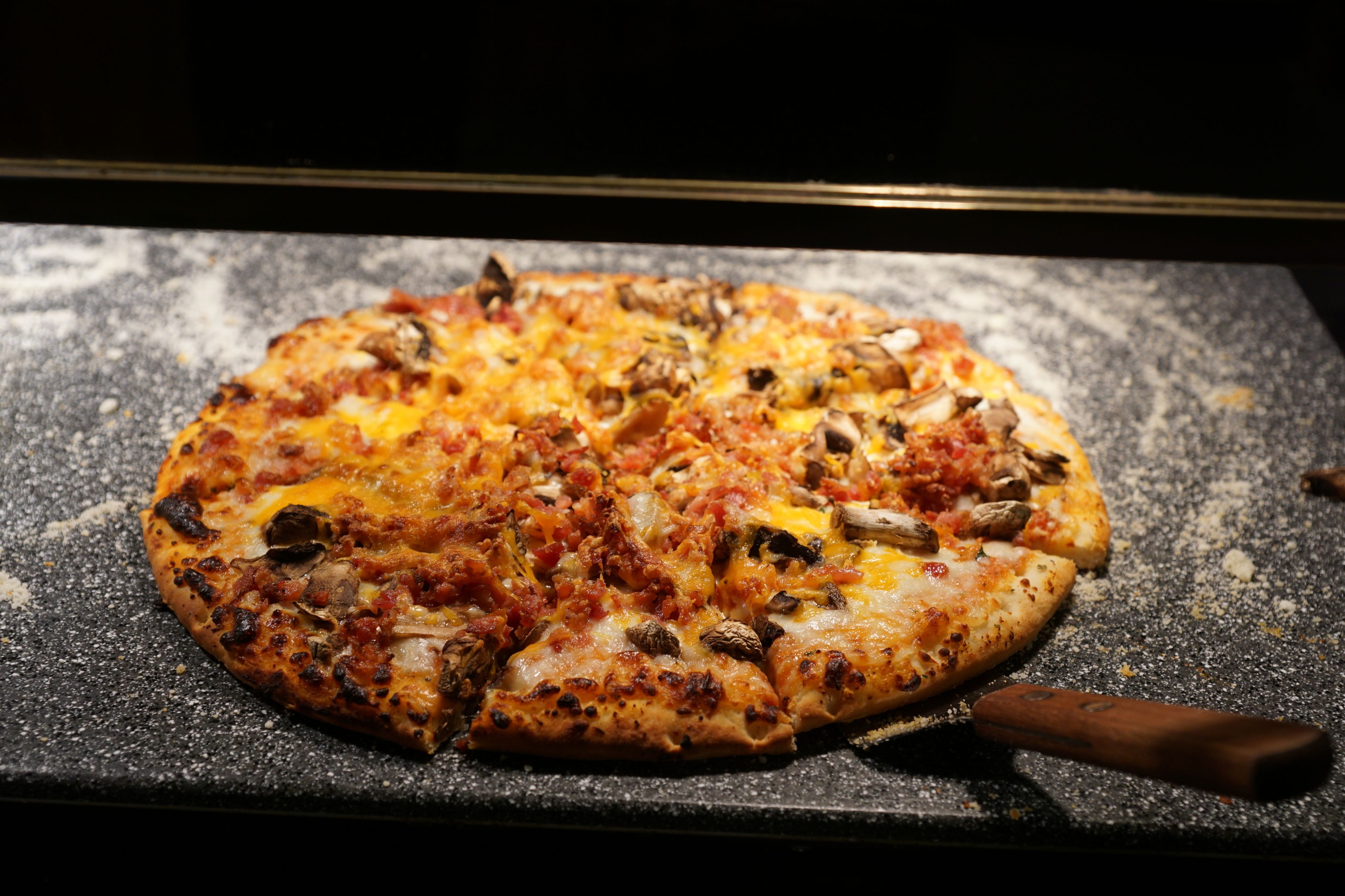 Una pizza con diversi condimenti su un piano nero.