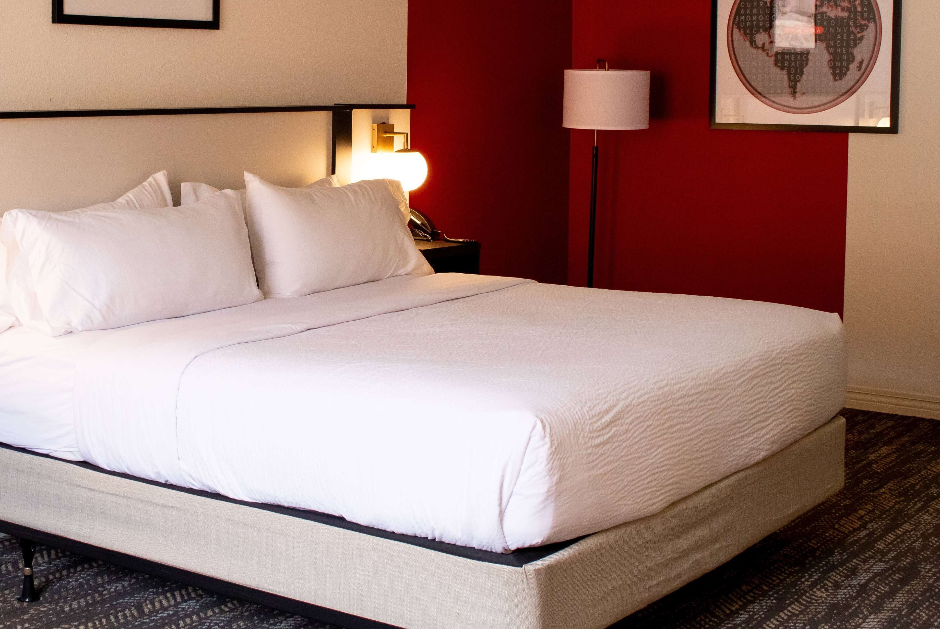 A neatly made bed with white linens in a hotel room.