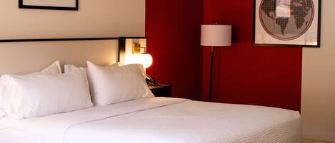 A neatly made bed with white linens in a hotel room.