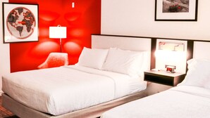 Una habitación de hotel con una cama grande, una mesita de noche con lámpara y un mapa del mundo en la pared.