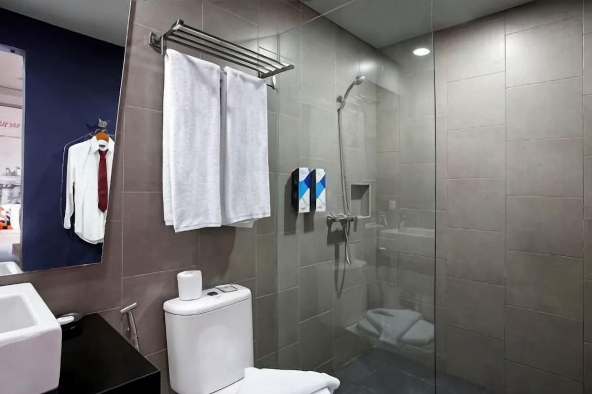 A modern bathroom with a glass shower enclosure, a toilet, and a sink.