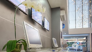 A reception desk with a desktop computer, a tablet, and a potted plant. - Berry Biz Hotel Powered by Archipelago (Legian)