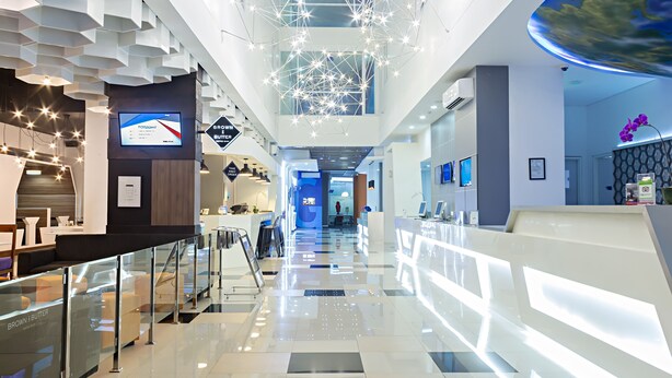 A modern hotel lobby with a glass railing, a reception desk, and a digital display. - Berry Biz Hotel Powered by Archipelago (Legian)