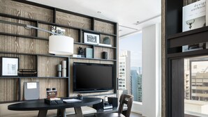 Ein modernes Wohnzimmer mit großem Flachbildfernseher, einem Esstisch mit Stühlen und einer Bücherwand.