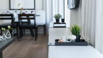 Un salón moderno con un sofá, una mesa de centro con una planta y un comedor al fondo.