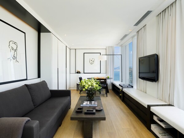 A modern living room with a sofa, a coffee table, and a TV mounted on the wall.