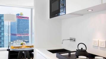 A modern kitchen with a built-in microwave, a sink, and a kettle on the counter.
