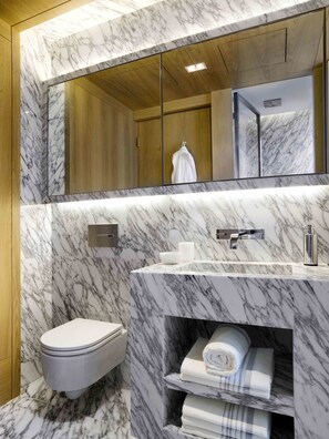A modern bathroom with a marble vanity, a toilet, and a mirror.