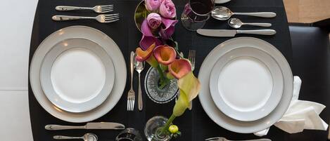 A dining table set with plates, cutlery, and a vase of flowers.
