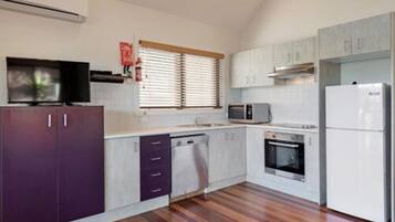 Una cocina moderna con armarios blancos, microondas, refrigerador y lavavajillas.