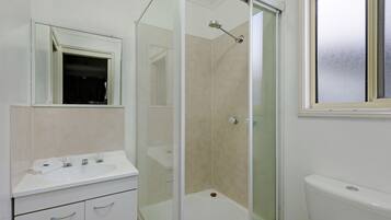 A bathroom with a glass-enclosed shower, a white sink, and a toilet.