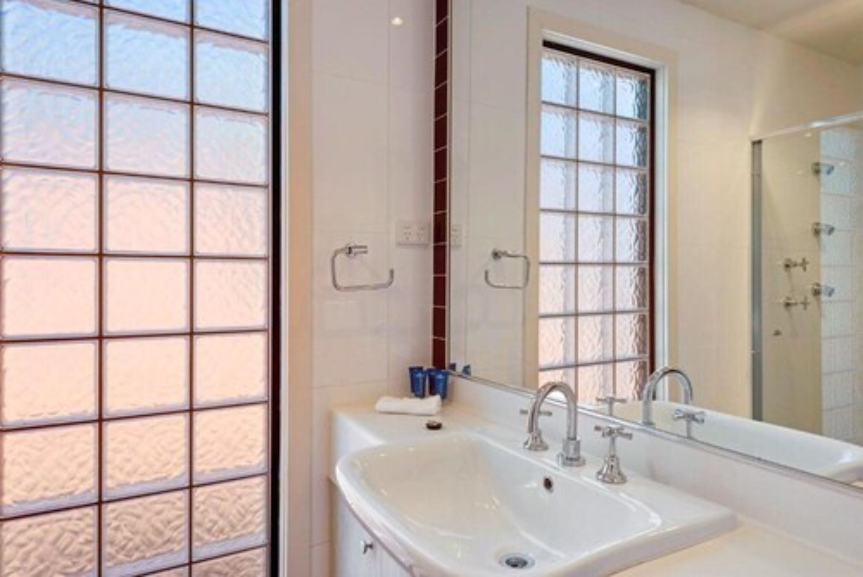Une salle de bain avec une grande fenêtre, un lavabo et un miroir.
