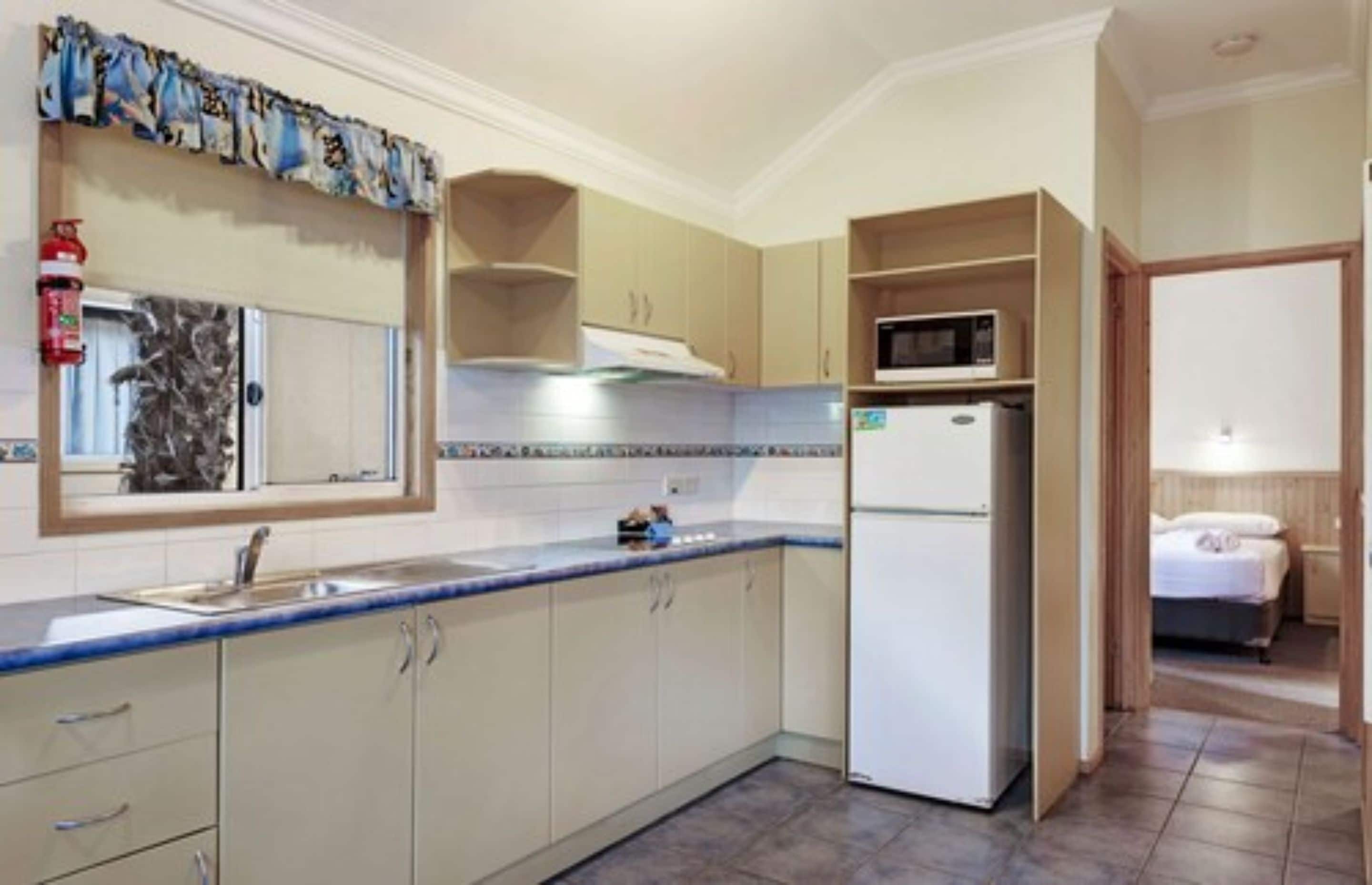 A compact kitchen with a microwave, refrigerator, and sink.