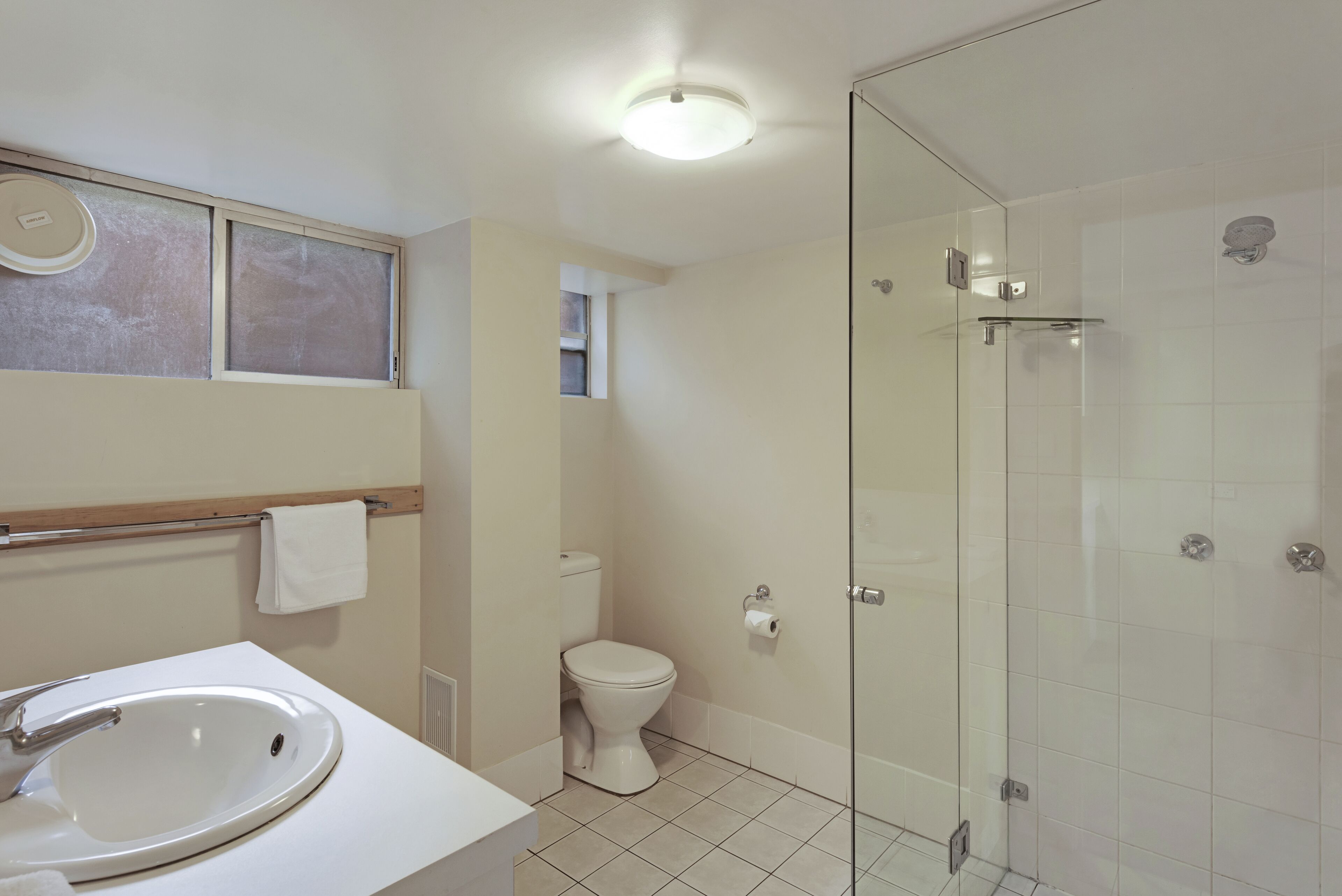 Une salle de bain avec un lavabo blanc, des toilettes et une douche à parois de verre.