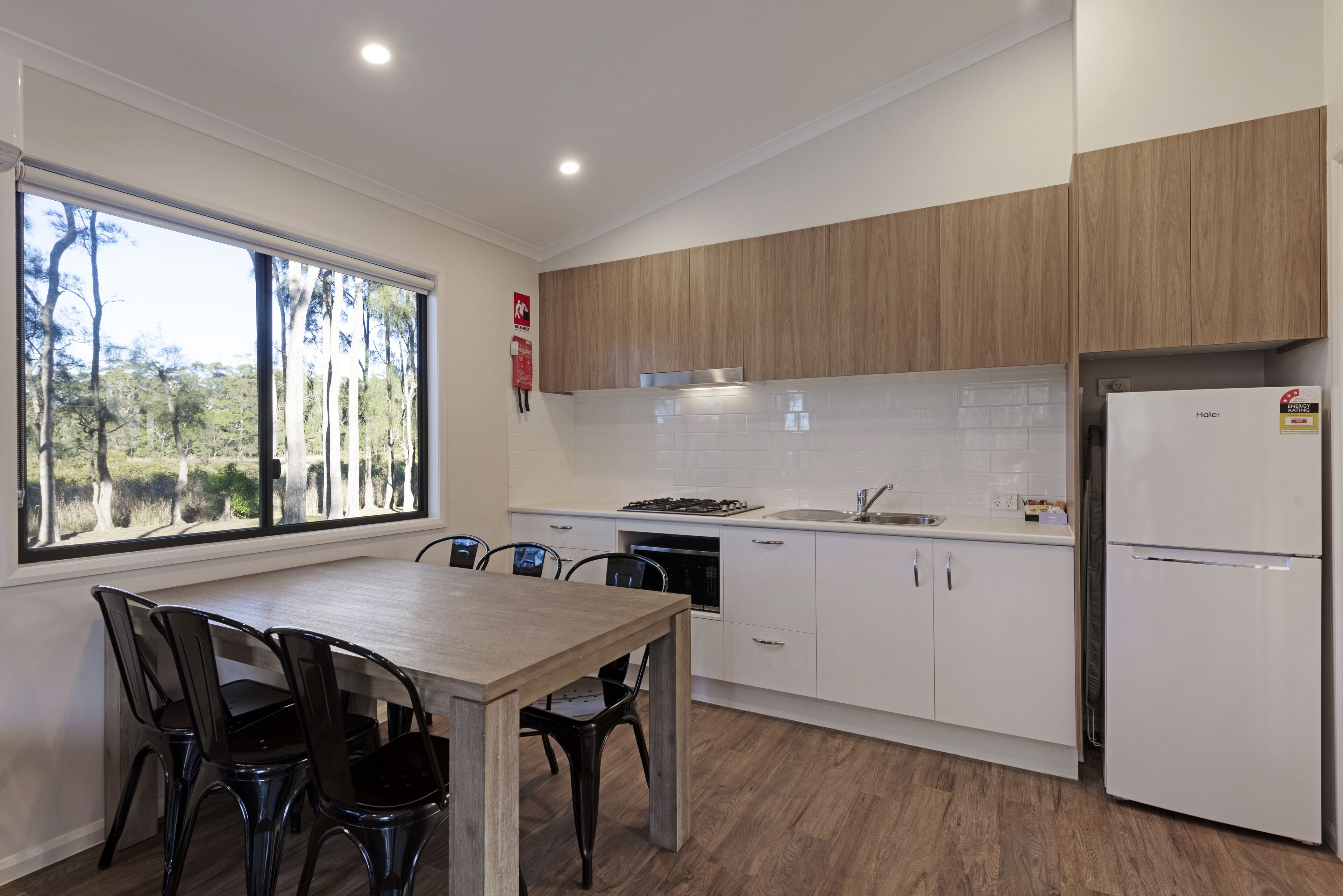 Una cocina moderna con encimera de madera, armarios blancos y una zona de comedor con mesa y sillas.