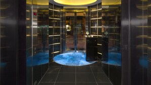 A modern elevator with a circular light fixture and reflective glass panels. - The Putman (Hong Kong)