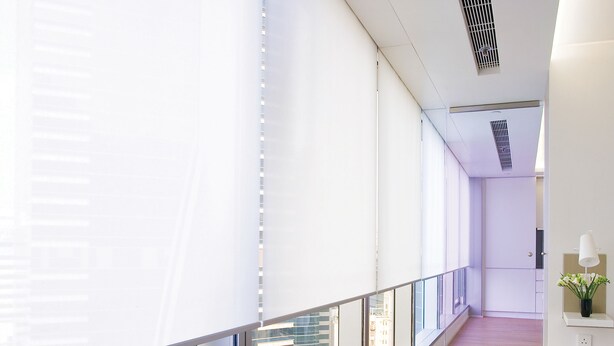 A corridor with large windows, a wooden floor, and a view of a cityscape. - The Putman (Hong Kong)