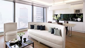 A modern living room with a sofa, coffee table, and a dining area with a table and chairs. - The Putman (Hong Kong)