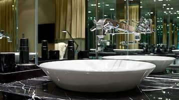A modern bathroom with a large white sink, black marble countertop, and a glass shower enclosure.