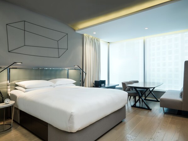 A modern hotel room with a large bed, bedside tables, a desk, and a chair.