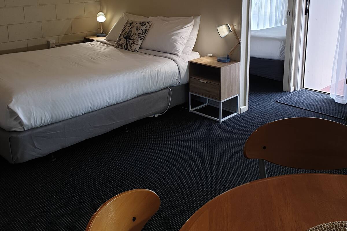 Ett hotellrum med en säng, sängbord, en stol och en dörr som leder ut till en balkong.