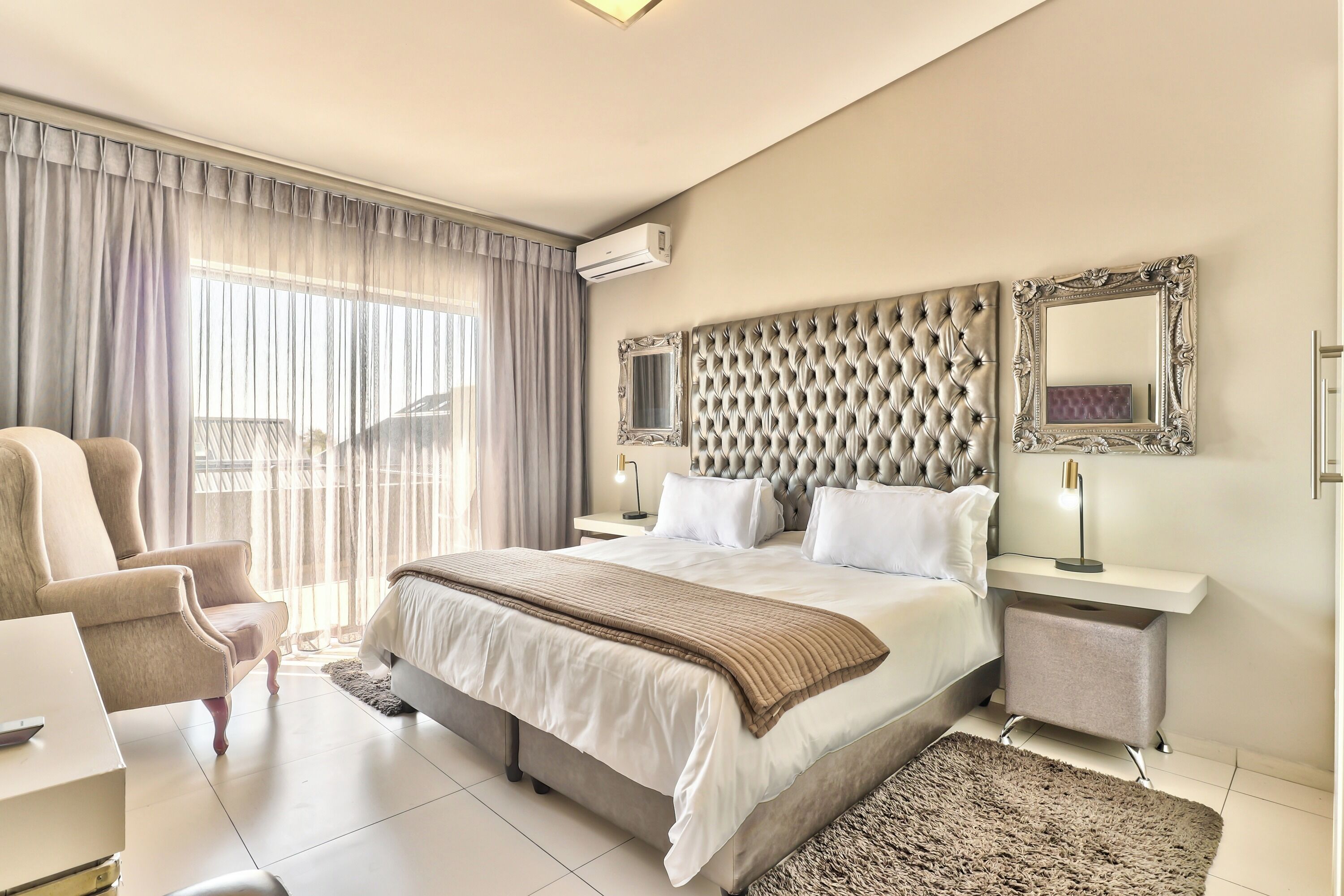 Quarto de hotel com uma cama grande, uma cadeira, uma escrivaninha e vista para o exterior.